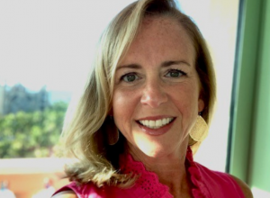 Woman with blonde hair smiling wearing a pink shirt